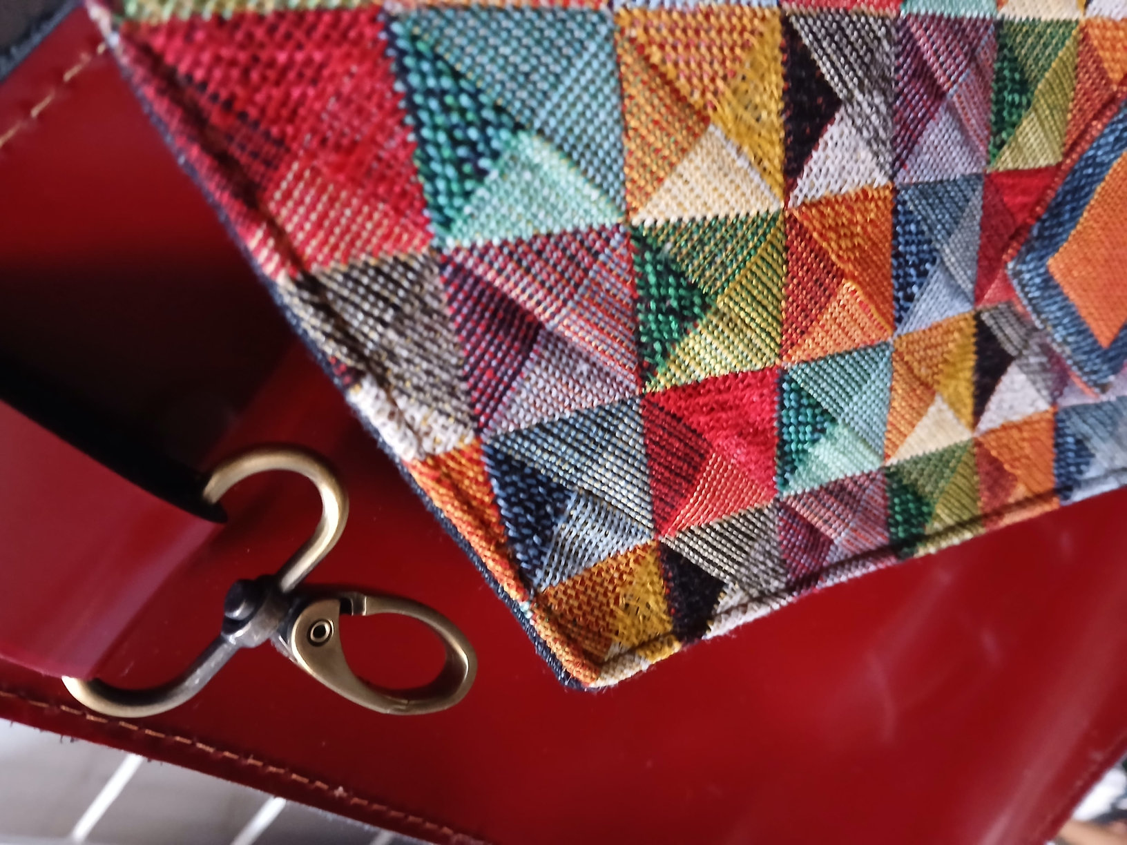 Detail — messing musketon haak op rood leer