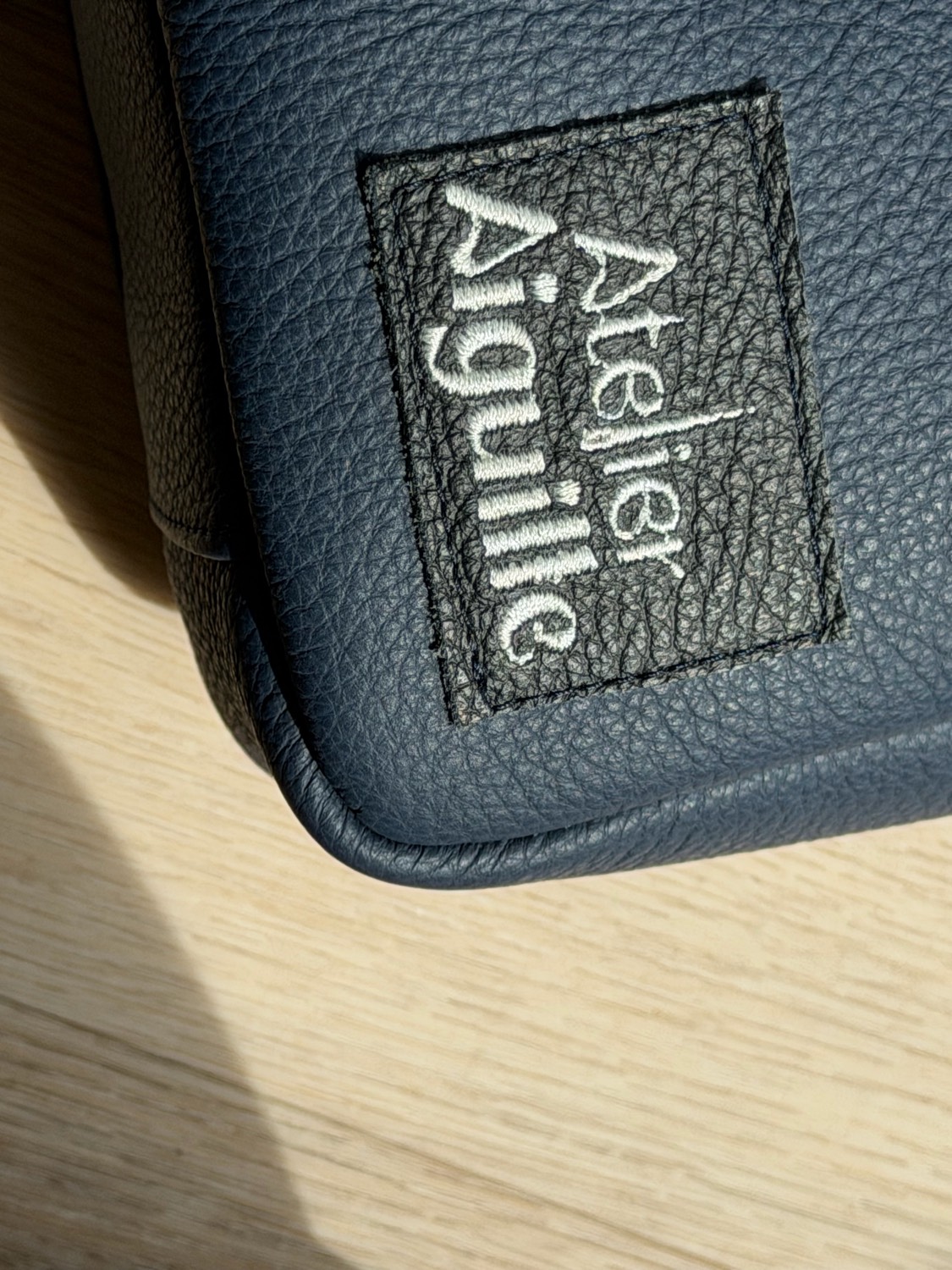 Geborduurd Atelier Aiguille label op donkere leren tas